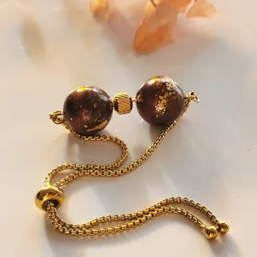 Bracelet ajustable en acier inoxydable doré avec deux perles artisanales en pâte polymère marron effet marbré et feuilles d'or.