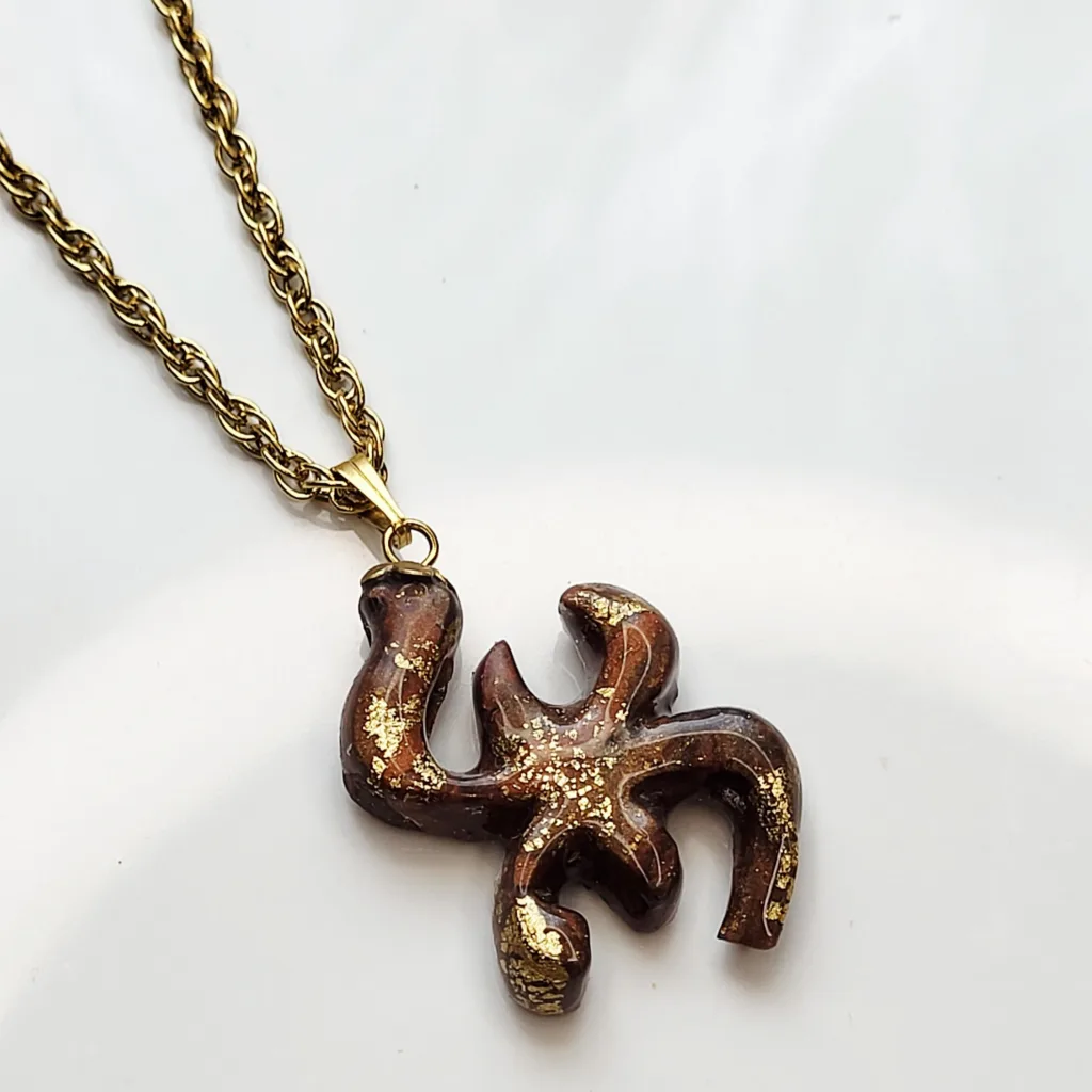 Collier artisanal symbole berbère Aza en pâte polymère marron et éclats d'or sur chaîne en acier inoxydable.