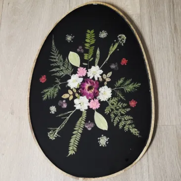 Plateau ovale artisanal en bois de manguier avec inclusion de fleurs séchées blanches et roses dans de la résine noire.