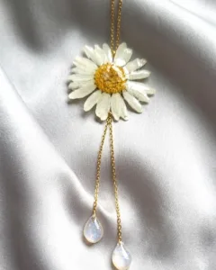 Gros plan sur le pendentif marguerite en résine artisanale avec ses détails dorés