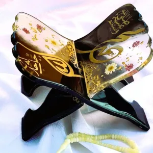 Support de livre sacré Rahl en résine époxy assemblé en forme de X, révélant des détails de calligraphie islamique dorée et de véritables fleurs séchées suspendues dans la matière.